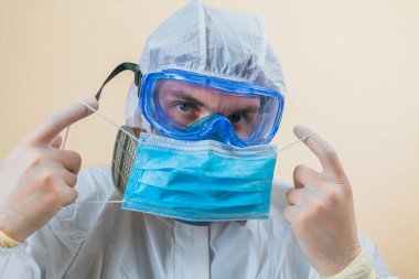 Doktor sarı arka planda tıbbi maske tutuyor..