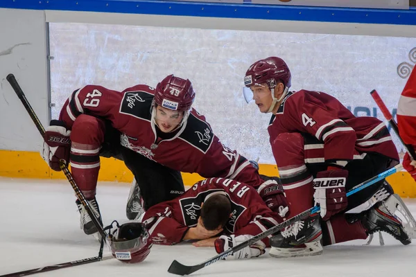 Riga, Letonya. 14 Kasım 2019. Emils Gegeris (L) ve Nerijus Alisauskas (R), Kontinental Hokey Ligi (Khl) 2019 / 2020 sezonunda buz üzerinde yatan takım arkadaşları Mikelis Redlihs 'e (C) yardım ediyor.
