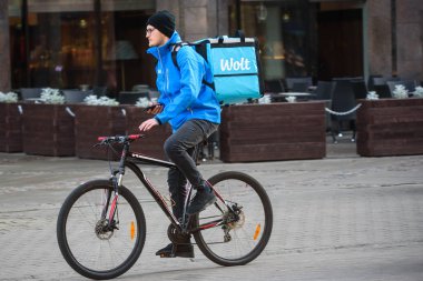 Riga, Letonya. 16 Ekim 2019. Wolt Şirketi 'nin yemek teslimatı. Bisikletli genç adam akıllı telefonu elinde tutuyor..
