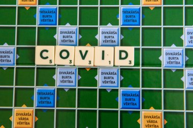 RIGA, LATVIA. 3 Mayıs 2020. Scrabble oyununda COVID adı. Scrabble, iki ila dört oyuncunun kiremit yerleştirerek puan aldığı bir kelime oyunudur..