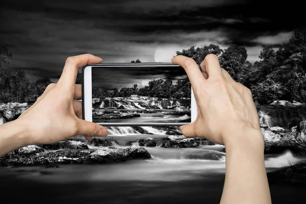 Flicka som tar bilder på smarta mobiltelefon i mörkt vattenfall — Stockfoto