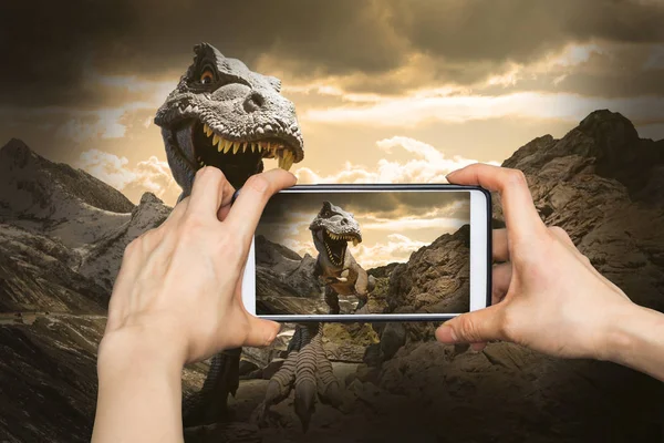Fotograferen op mobiele slimme telefoon in dinosaurussen model op rots — Stockfoto