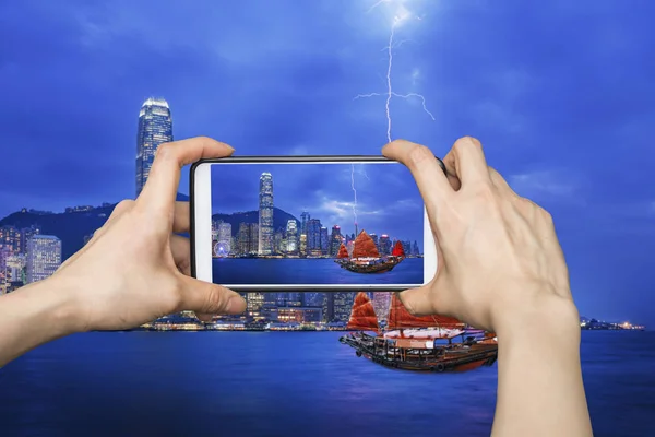 Chica tomando fotos en el teléfono inteligente móvil en Hong Kong paisaje urbano — Foto de Stock
