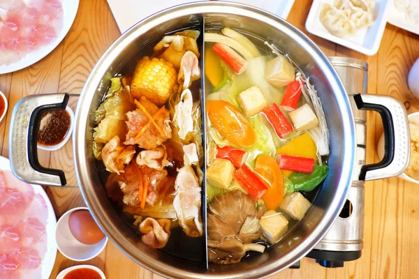 Double flavor hot pot on wood background — Stock Photo, Image