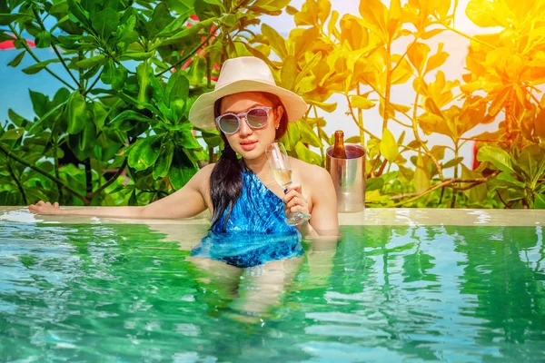 Hermosa mujer joven en la piscina con un champán en su h — Foto de Stock