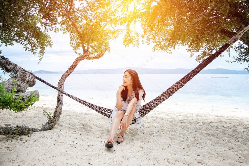 Beautiful woman sitting on a swing on the beach  in Koh Phangan,