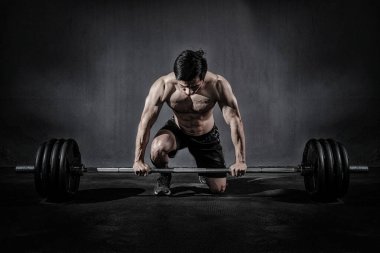 Güçlü fitness adamı spor salonunda halterlerle kol egzersizi yapıyor.