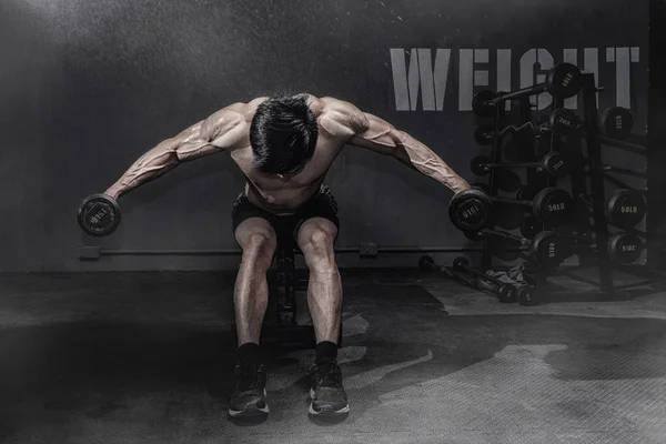 Hombre fuerte de fitness haciendo ejercicio de brazo con mancuernas en el gimnasio — Foto de Stock