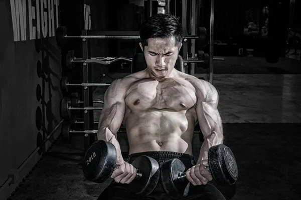 Erős fitness férfi csinál kar edzés súlyzókkal a tornateremben — Stock Fotó