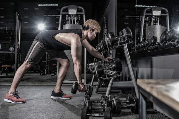 Hombre fuerte de fitness haciendo ejercicio de brazo con mancuerna en el gimnasio — Foto de Stock