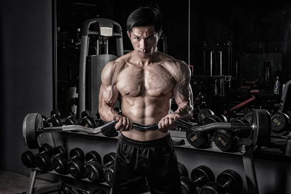 Forte uomo di fitness che fa allenamento del braccio con i bilancieri in palestra — Foto Stock