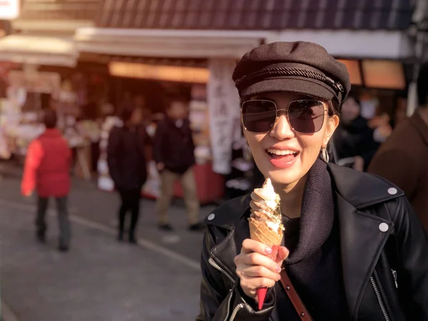 Young tourist woman eating ice cream cone covered with real gold
