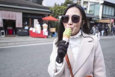Japonya 'daki Arashiyama bambu ormanında dondurma yiyen genç turist kadın.