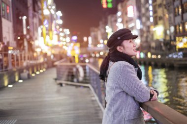 Japonya 'nın Osaka kentindeki Dotonbori caddesinde yürüyen güzel gülümseyen kadın turistler..