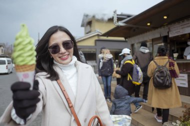 Japonya 'daki Arashiyama bambu ormanında dondurma yiyen genç turist kadın.