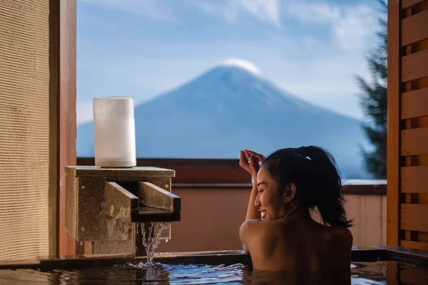 Güzel bir kadın sabahları Japonya 'daki Fuji Dağı' nın manzarasını izleyerek onsen 'in (mineral sıcak banyosu) tadını çıkarır. 