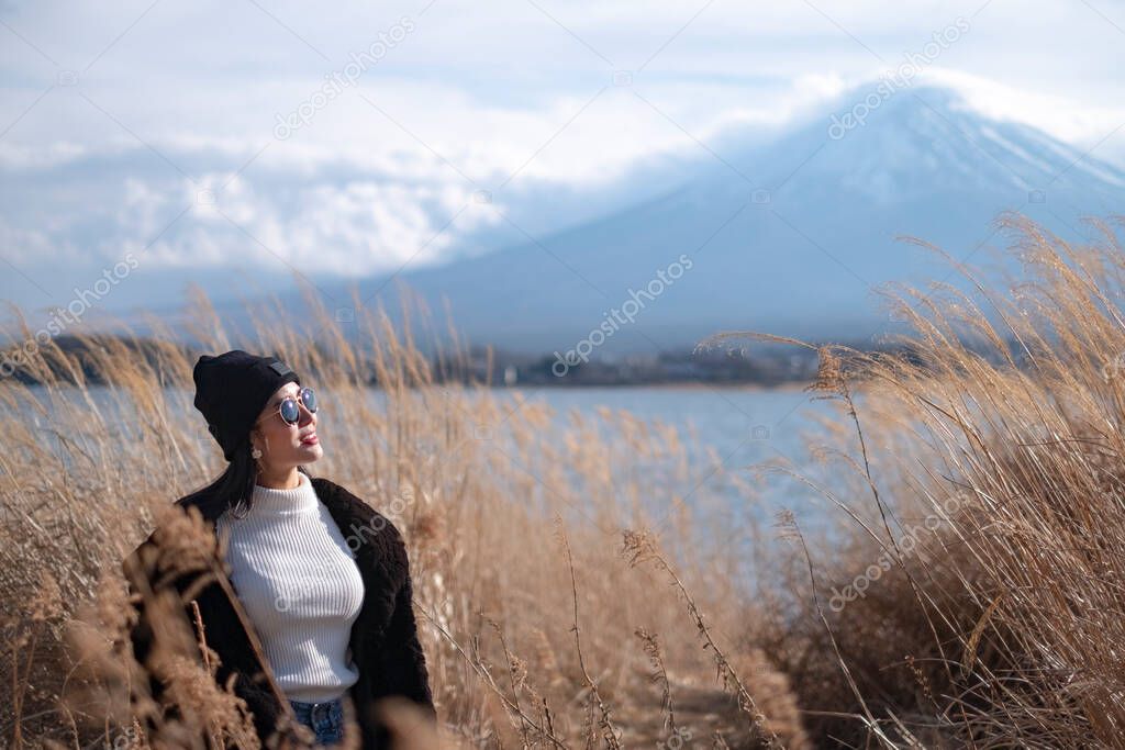 Beautiful smiling woman tourists are traveling and feel happy with Mt Fuji in the morning on the lake kawaguchiko, Japan
