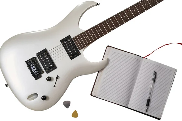Bovenaanzicht van close-up van witte elektrische gitaar, twee bemiddelaars, open notebook en pen. Werkruimte van muzikant. Geïsoleerd op witte achtergrond met knippad — Stockfoto