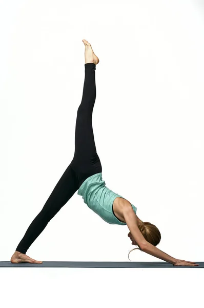 Portret młodej atrakcyjnej kobiety ćwiczącej na macie do jogi. Zdrowy styl życia i koncepcja sportu. Seria ćwiczeń stwarza. Odizolowane na biało — Zdjęcie stockowe