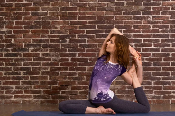 İnce vücutlu güzel bir kadın tuğla duvarda yoga yapıyor. 