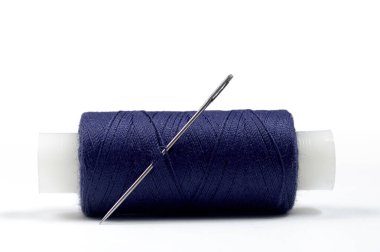 Beyaz arka planda çelik iğneyle dikilmiş mavi dikiş makarasının yakın çekimi