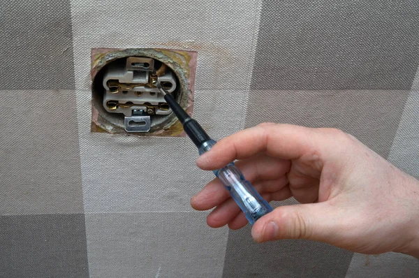 Repair of an electrical outlet in a city apartment. Visible insulated wires, disassembled power outlet. A hole has been made in the wall