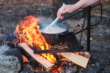 A woman is cooking a traditional Finnish soup at the campfire.