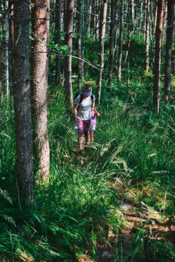 Mom and daughter are walking along a hiking trail in the forest.