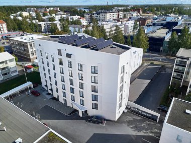 Aerial view of the white brand new apartment building with solar panels on the roof. clipart