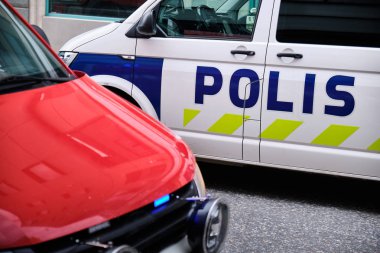 The fire car with a blue light and a police car on the street in Finland. clipart