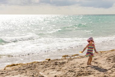 Çalışan ve güneşli bir da kumsalda oynarken mutlu küçük kız