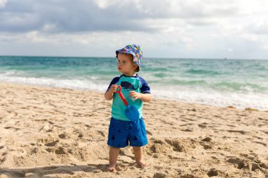 Güneşli bir gün boyunca bir plajda bir oyuncak kürek ile küçük çocuk