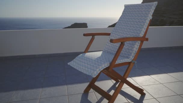 Empty Deck Chair On A Breezy Terrace By The Blue Sea In Summer Holiday Resort In Greece — Stock Footage Empty Deck Chair Breezy Terrace Blue Sea Summer Holiday Resort Stock Video