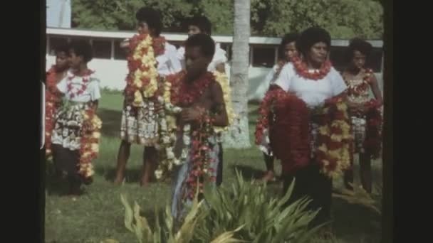 Francouzská Polynésie, Tonga, leden 1976. Tři zastřelil pořadí nativní tonžského žen, dětí a muži v tradičních úborech s náhrdelníkem květinové dekorace.