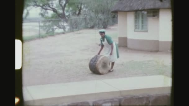 Jižní Afrika, Pretoria, květen 1976. Africká žena v pracovní oblečení bubenické sólo v zahradě.