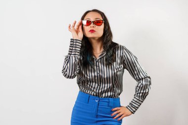 Mavi etekli ve kırmızı gözlüklü çizgili tişörtlü bir kız. beyaz arkaplan