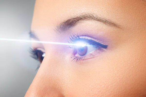 Női szemek közelről. Lézersugár a szaruhártyán. A lézeres látás korrekciójának koncepciója — Stock Fotó