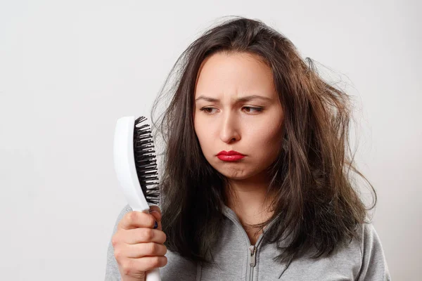 Saçları dağınık bir kız elinde tarak tutuyor.