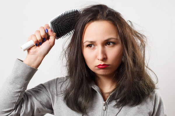 Девочка с заплетенными волосами держит в руках расческу
