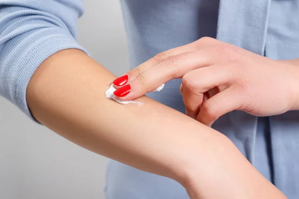 Kadın ellerine krem sürüyor.