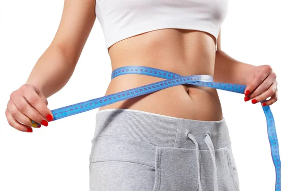 Genç, ince bir kadın belini bir santimetre bantla ölçüyor. beyaz arkaplanda izole