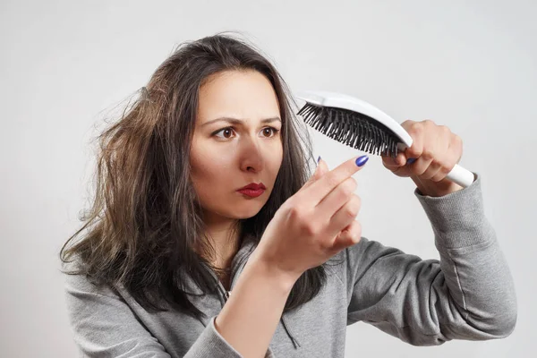 Saçları dağınık bir kız elinde tarak tutuyor.