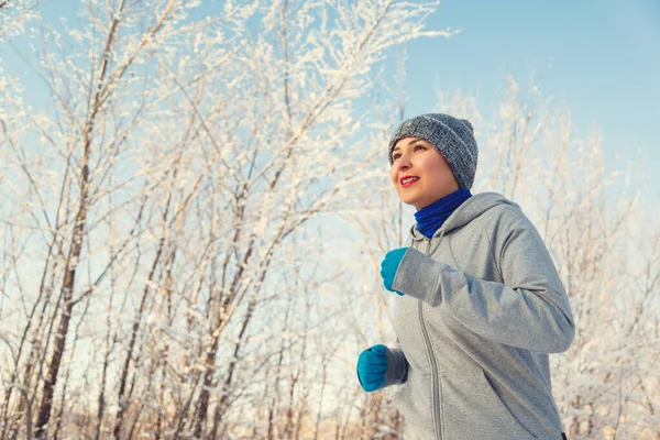 Systemem kobieta sport. Kobiece biegacza jogging w lesie Mroźna zima sobie ciepłe sportowy, running Odzież i rękawice. — Zdjęcie stockowe