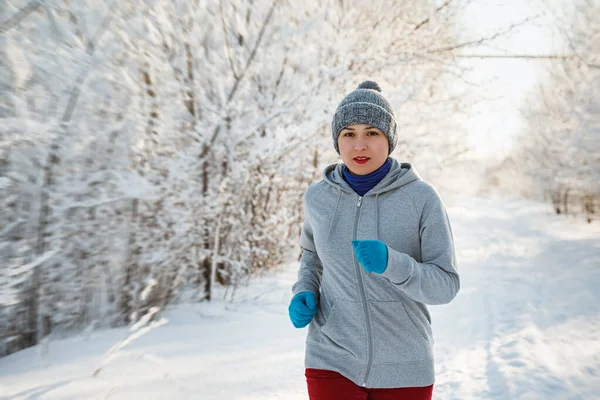 Spor kadın çalışıyor. Kadın atlet giyen sıcak giyim çalışan sportif ve eldiven soğuk kış ormanda koşu.