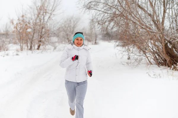 Systemem kobieta sport. Kobiece biegacza jogging w lesie Mroźna zima sobie ciepłe sportowy, running Odzież i rękawice — Zdjęcie stockowe