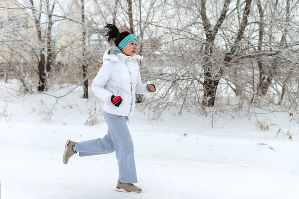 Systemem kobieta sport. Kobiece biegacza jogging w lesie Mroźna zima sobie ciepłe sportowy, running Odzież i rękawice — Zdjęcie stockowe