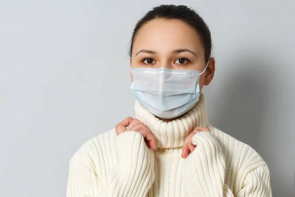 Studioporträt einer jungen Frau mit Gesichtsmaske, die in die Kamera blickt, aus nächster Nähe, isoliert auf grauem Hintergrund. Grippeepidemie, Stauballergie, Schutz vor Viren — Stockfoto