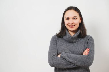 Güzel bir genç kızın portresi, önünde katlanmış eller, beyaz arka planda izole edilmiş..