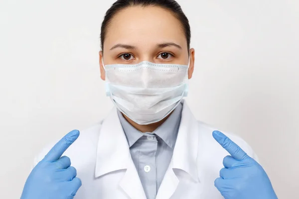 Female Doctor Dressing Gown Gloves Points Her Hands Protective Respiratory — Stock Photo, Image