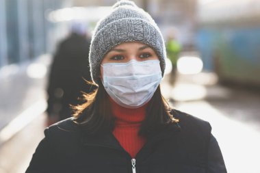 Şehir caddesinde tek kullanımlık koruyucu maskeli genç Avrupalı kadın. 2019-nCoV grip koronavirüsü konsepti Çin 'de mutasyona uğradı ve yayıldı.